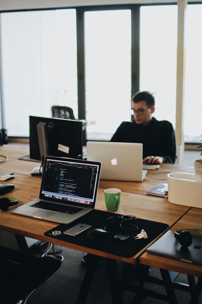 contact-img A web developer working on code in a modern office setting with multiple devices.